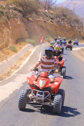 A line of quad riders on a mountain road