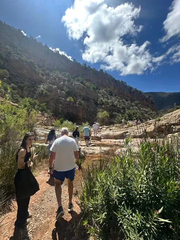 Visitors walking through the green valley between rocky mountains