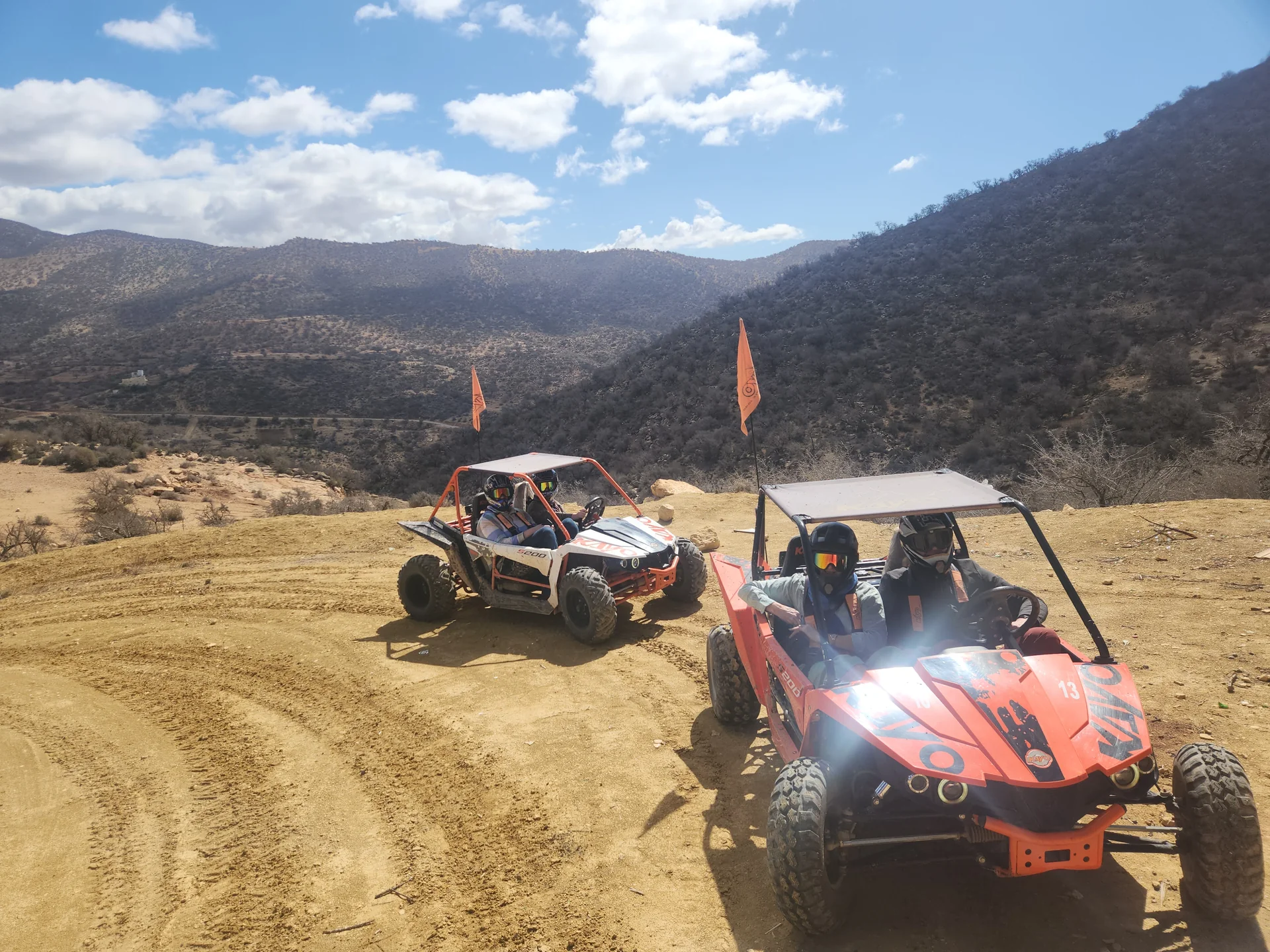 Buggies with helmeted riders on a mountain trail