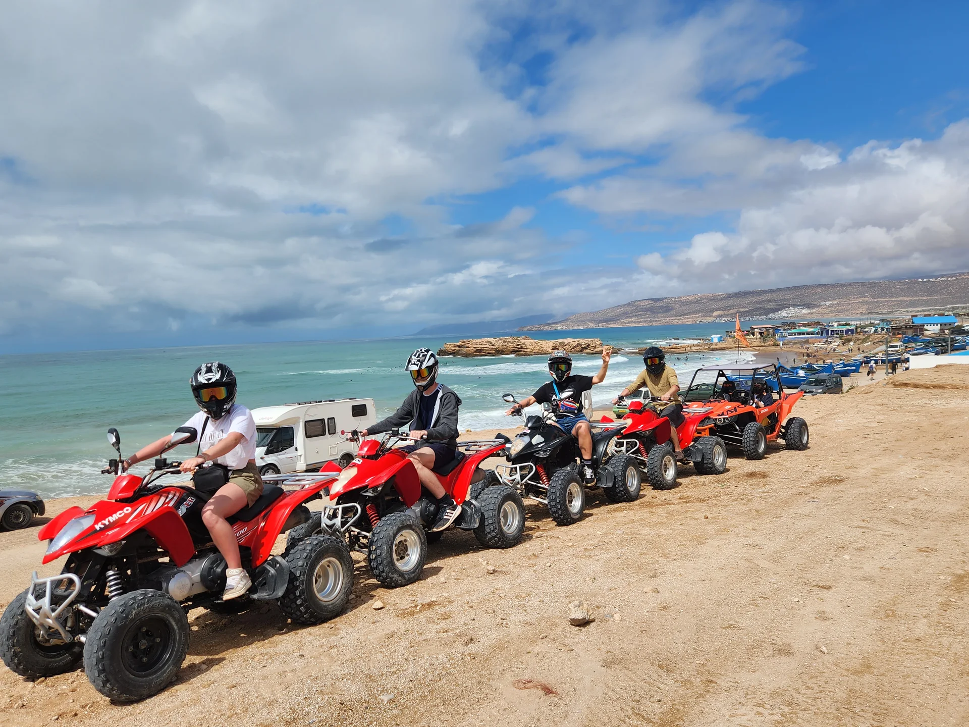 Helmeted guests on red quad bikes beside the coast