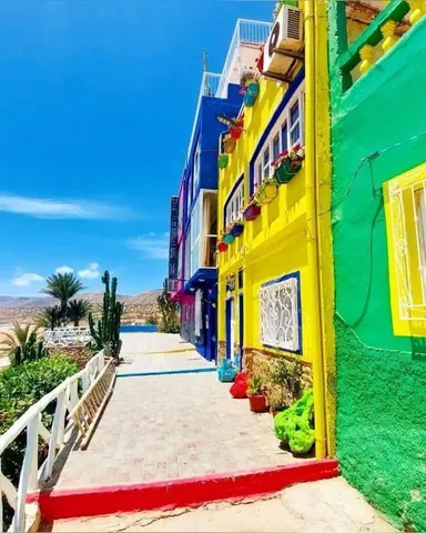 Blue, yellow, and green houses beside a path in Aghroud