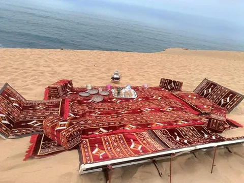 Tea served on a carpet with cushions on the dunes above the ocean