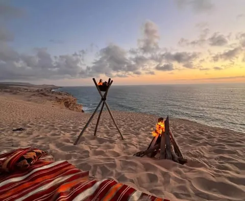 A seaside tea setup on the dunes at sunset