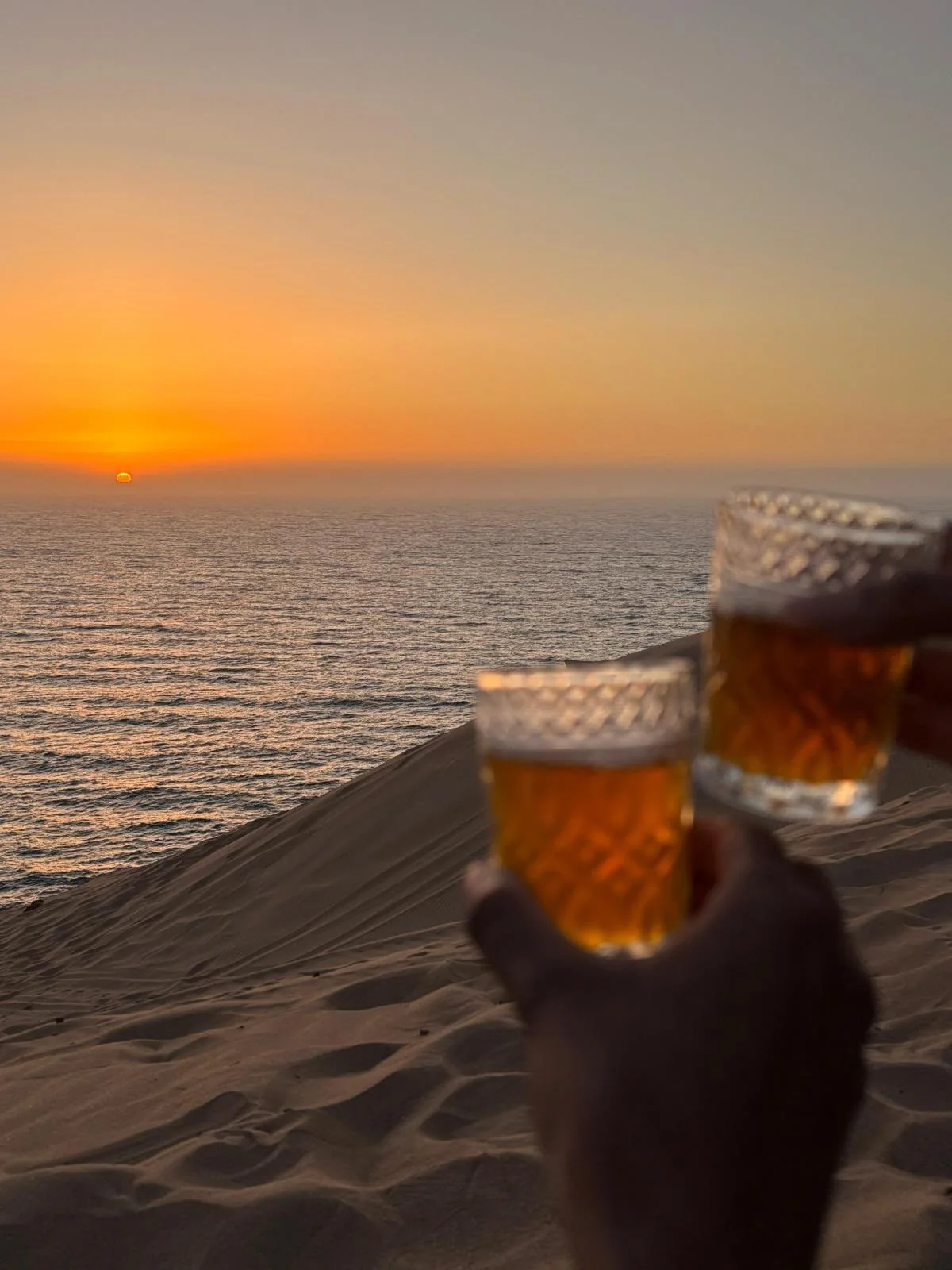 Glasses of Moroccan tea overlooking the ocean at sunset